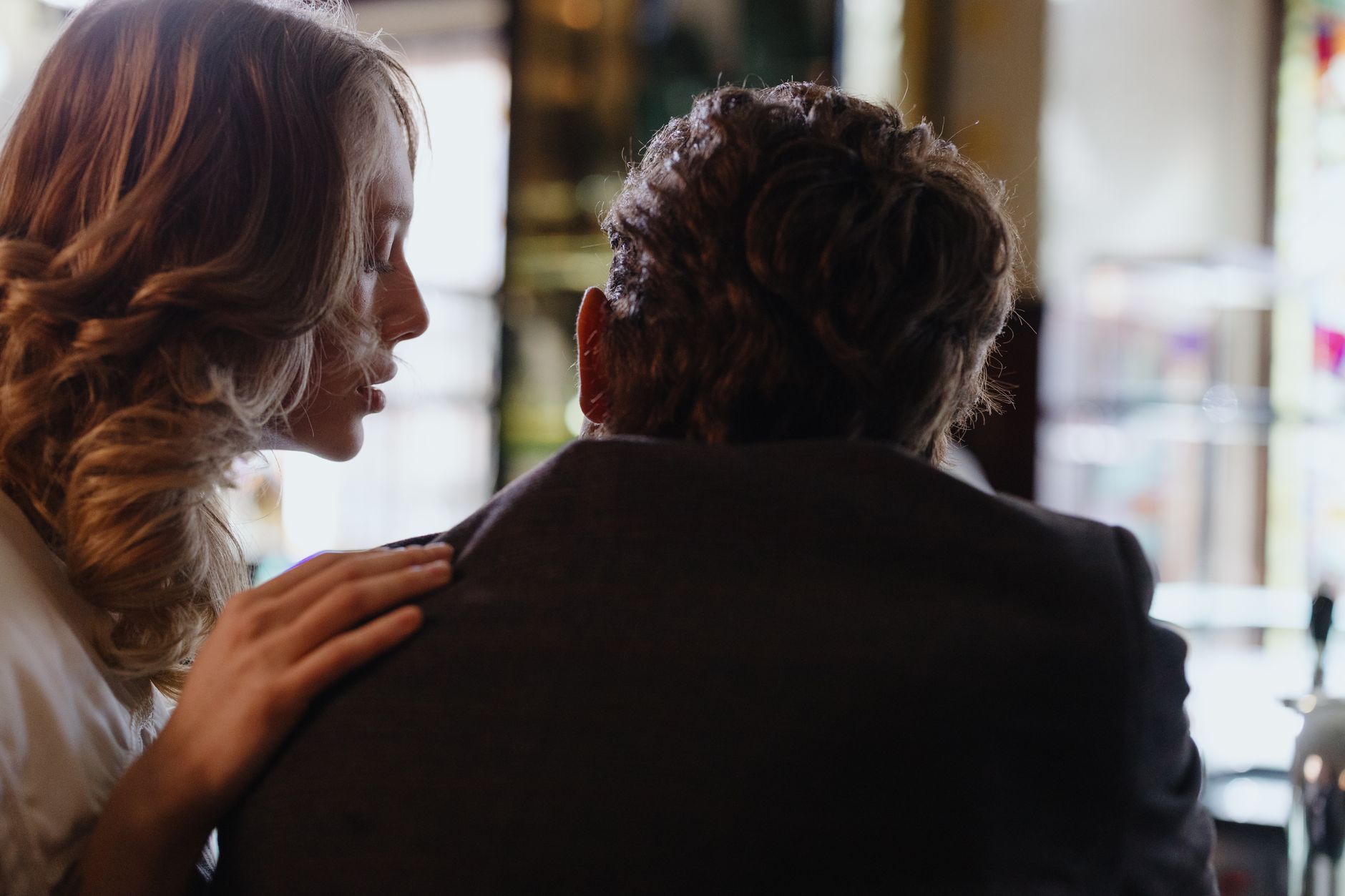 Close, intimate moment as two adults share a whisper in a softly lit room.