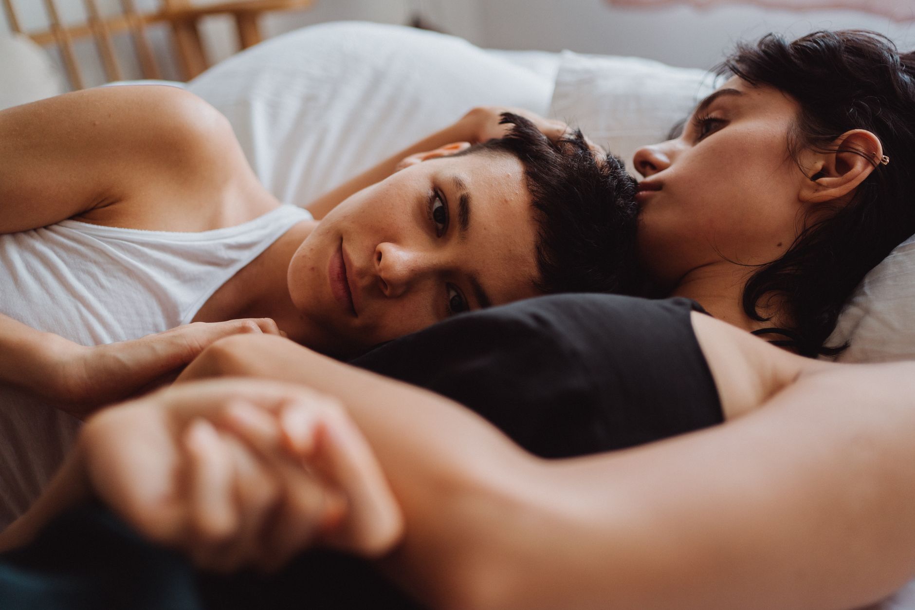 A tender moment capturing a loving couple embracing intimately in bed, conveying warmth and affection.