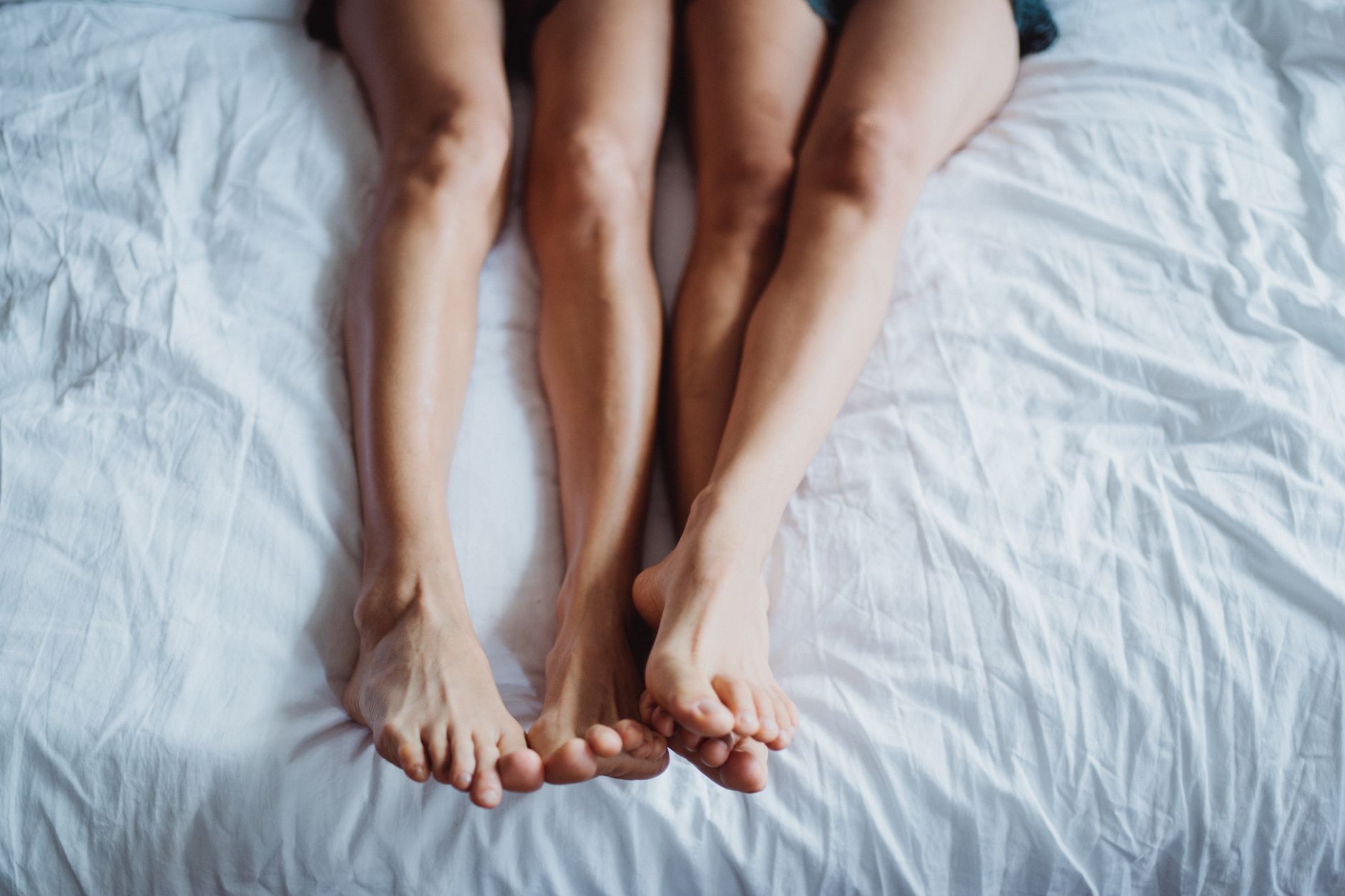 A couple lying in bed with their bare feet showing, creating a serene and intimate atmosphere.