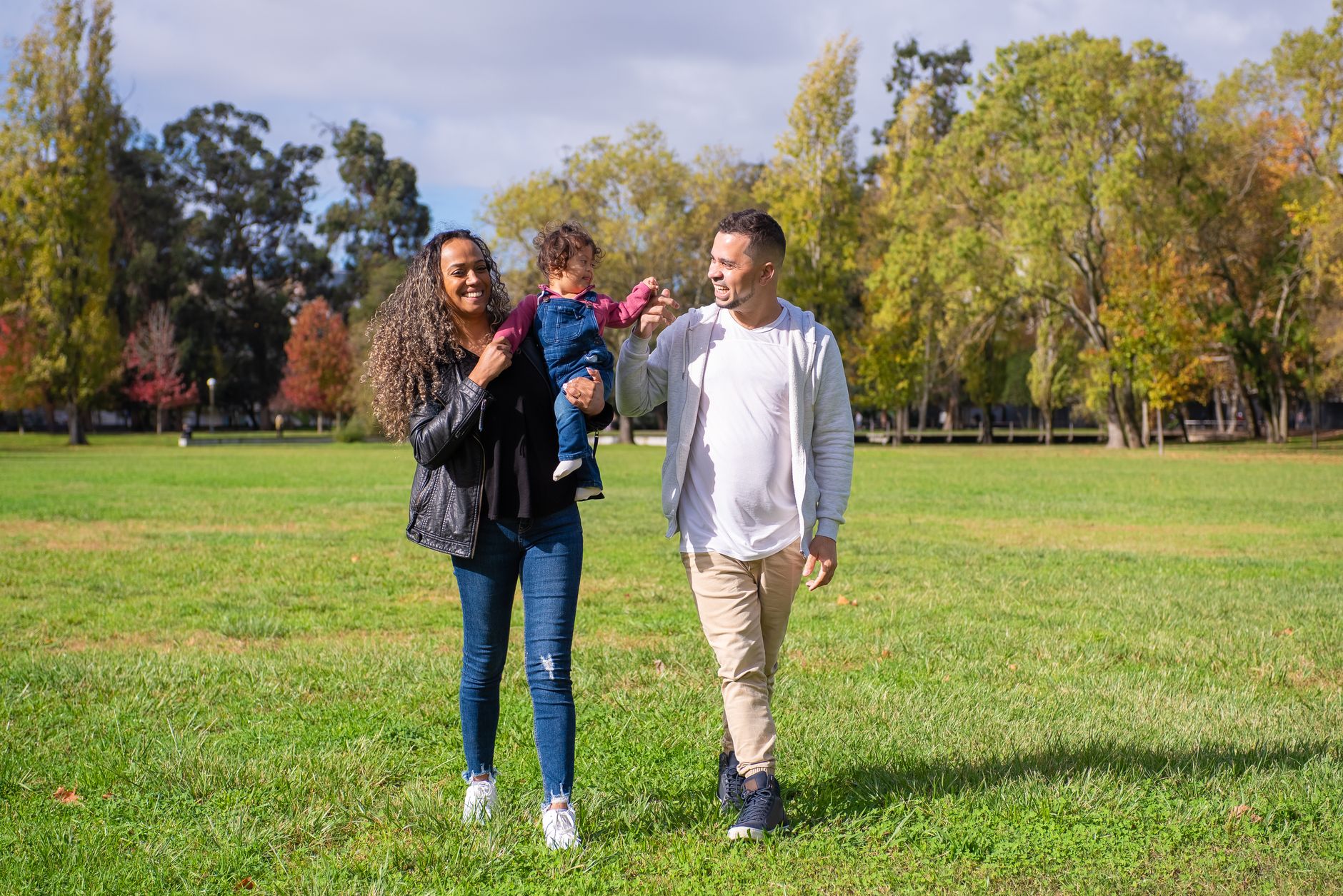 A joyful family walking in a sunny park, enjoying quality time together.