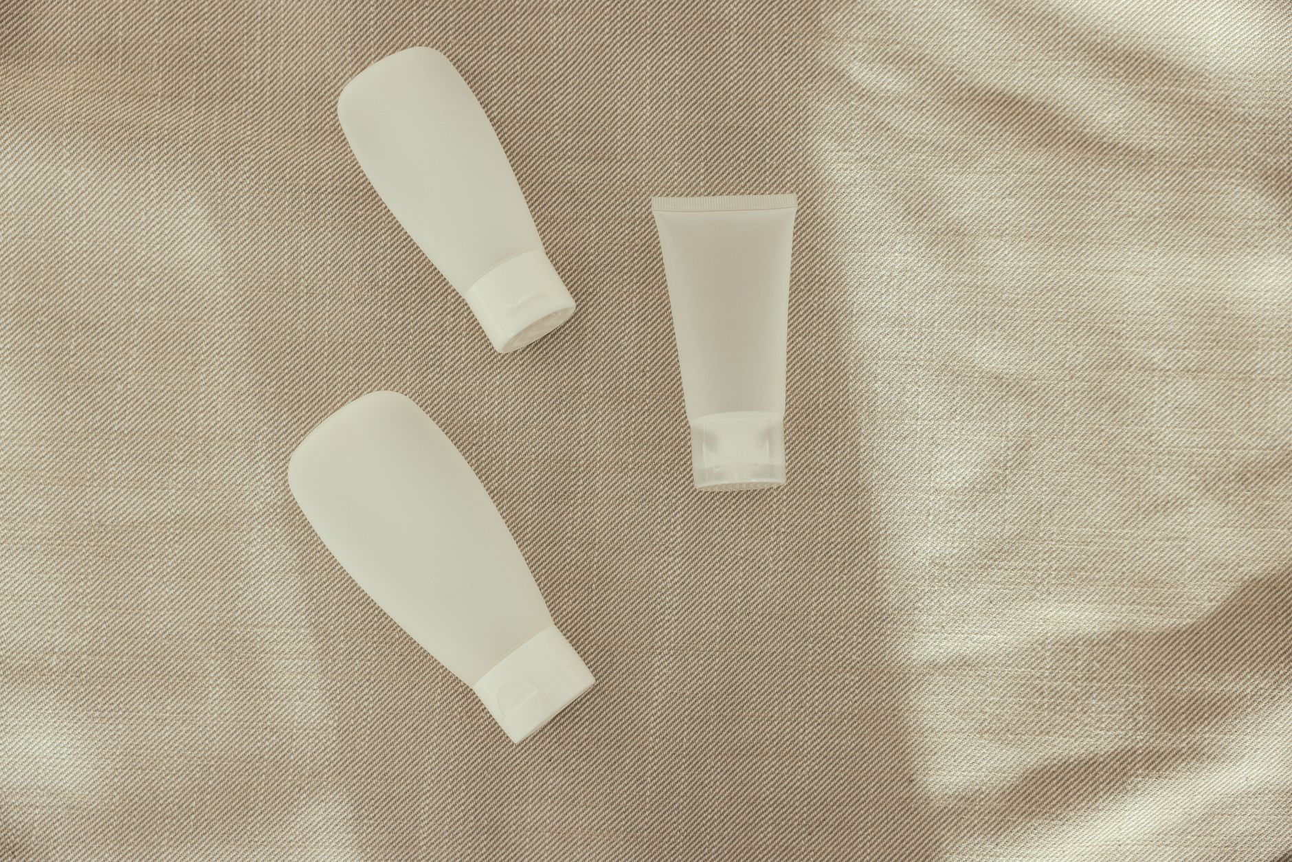 Flat lay image of minimalist plastic squeeze bottles on a textured surface.