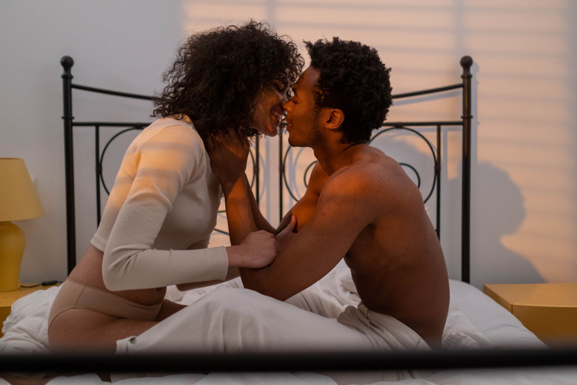 An intimate moment between a couple in a softly lit bedroom, capturing romance and affection.