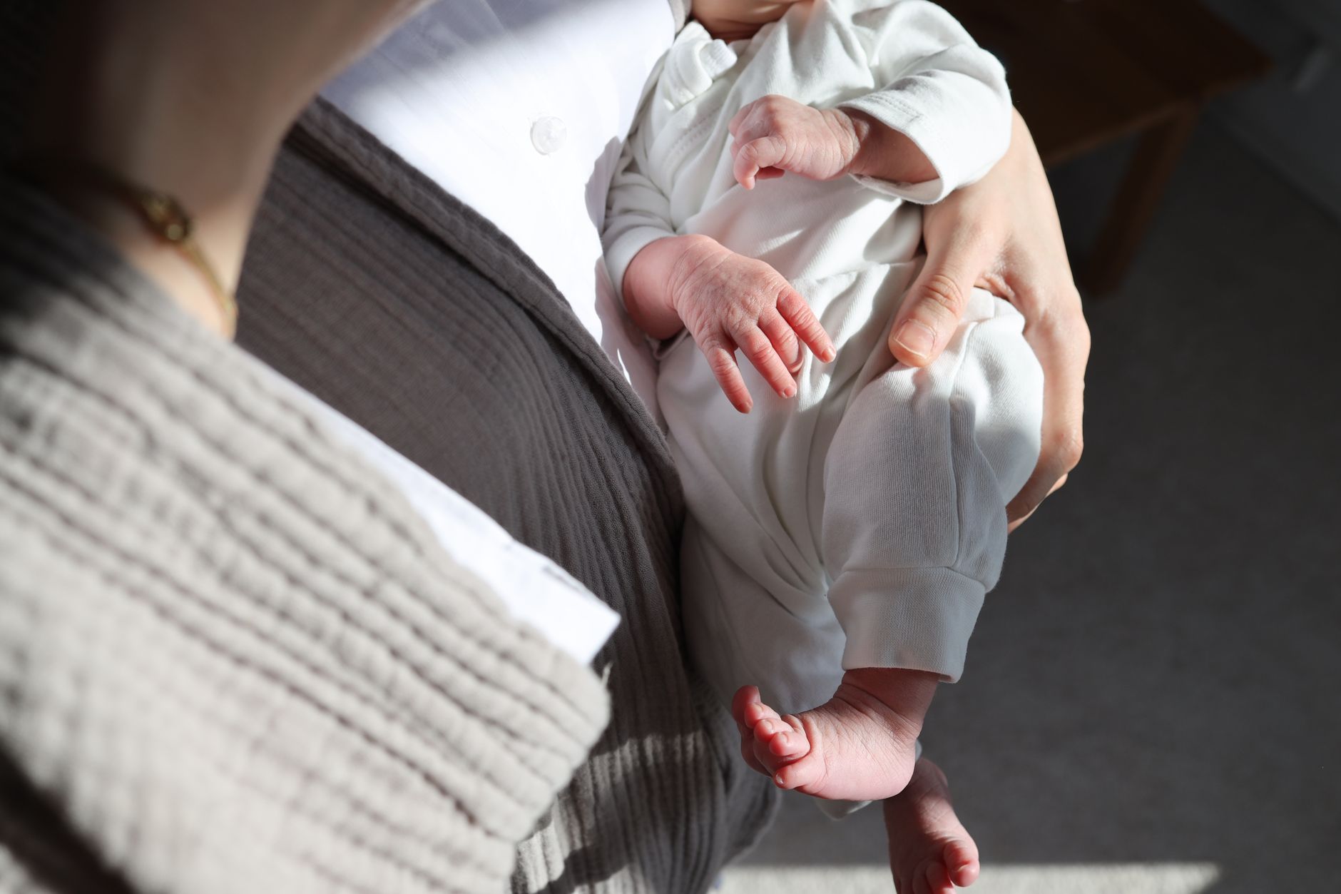 A mother lovingly cradles her newborn in a sunlit room, highlighting tender moments.
