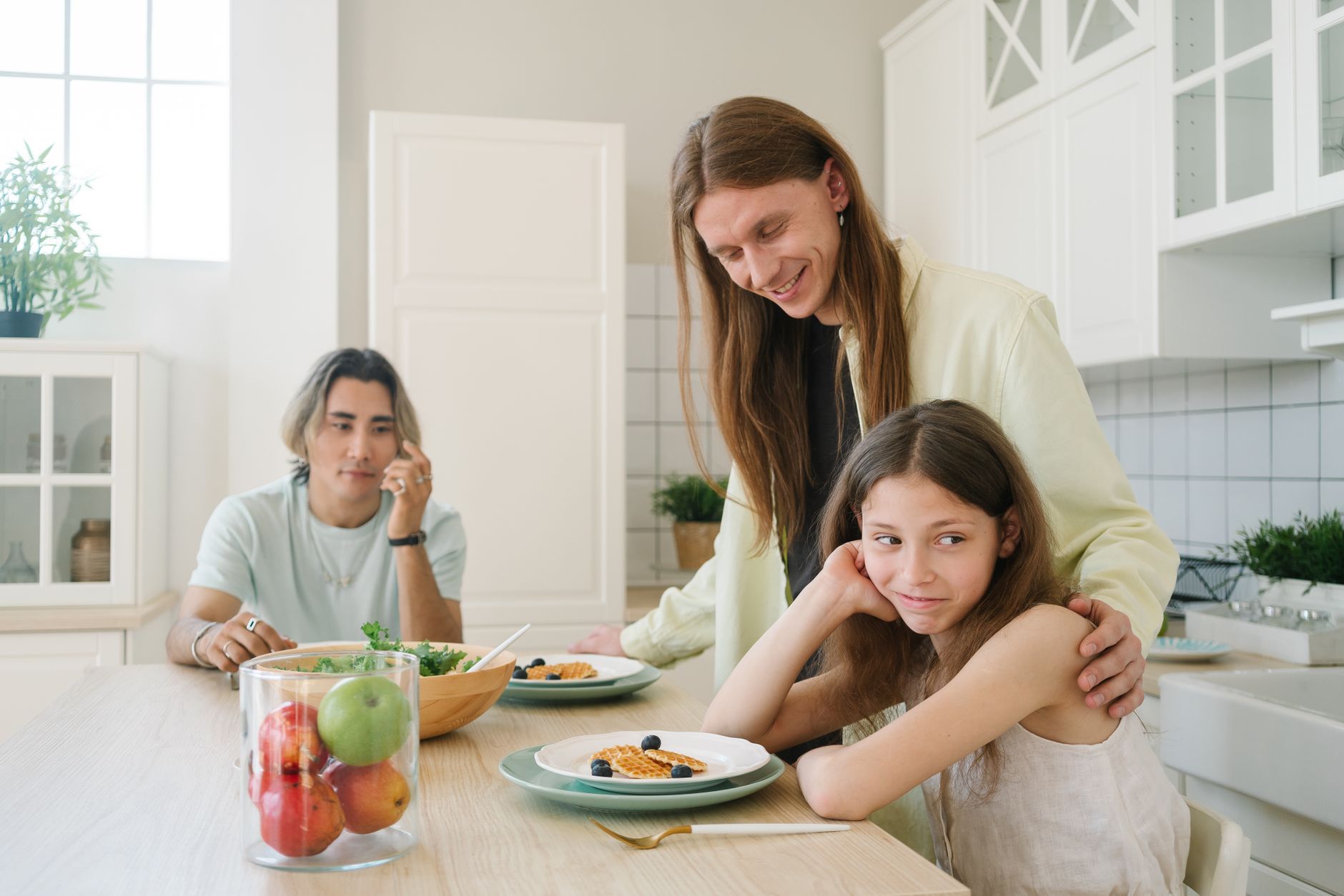 A family enjoys breakfast together in a bright, modern kitchen setting.