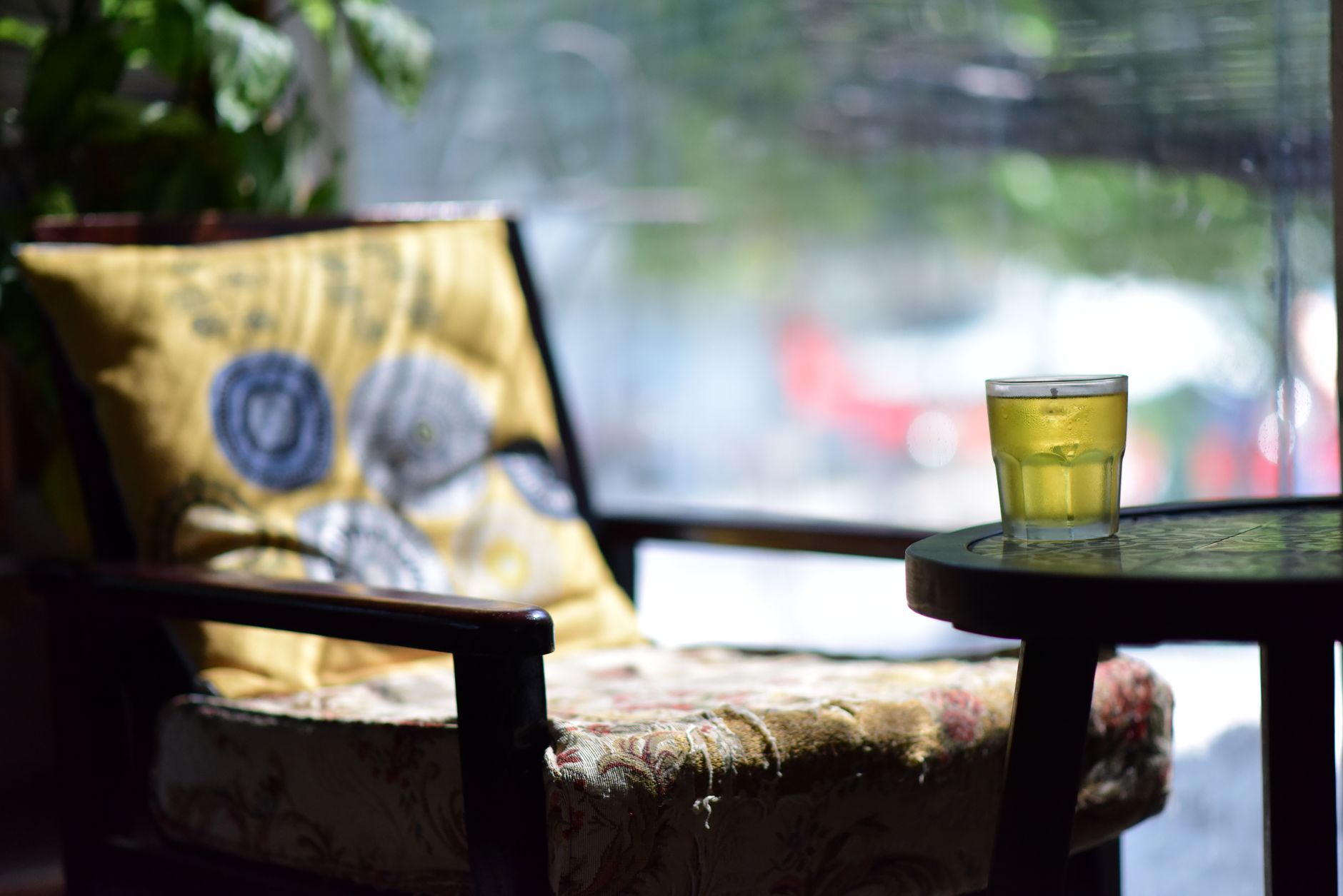 A cozy cafe scene featuring an intricately decorated chair and a refreshing glass of iced tea on a table.