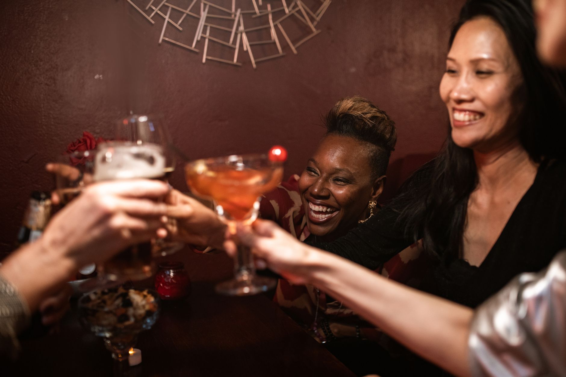 A cheerful group of friends toasting with drinks in a cozy indoor bar setting.