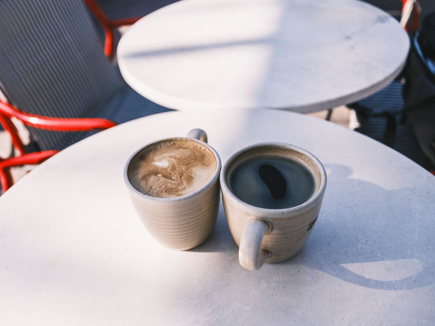 Charming café scene with two coffees on a sunlit table, perfect for relaxing moments.