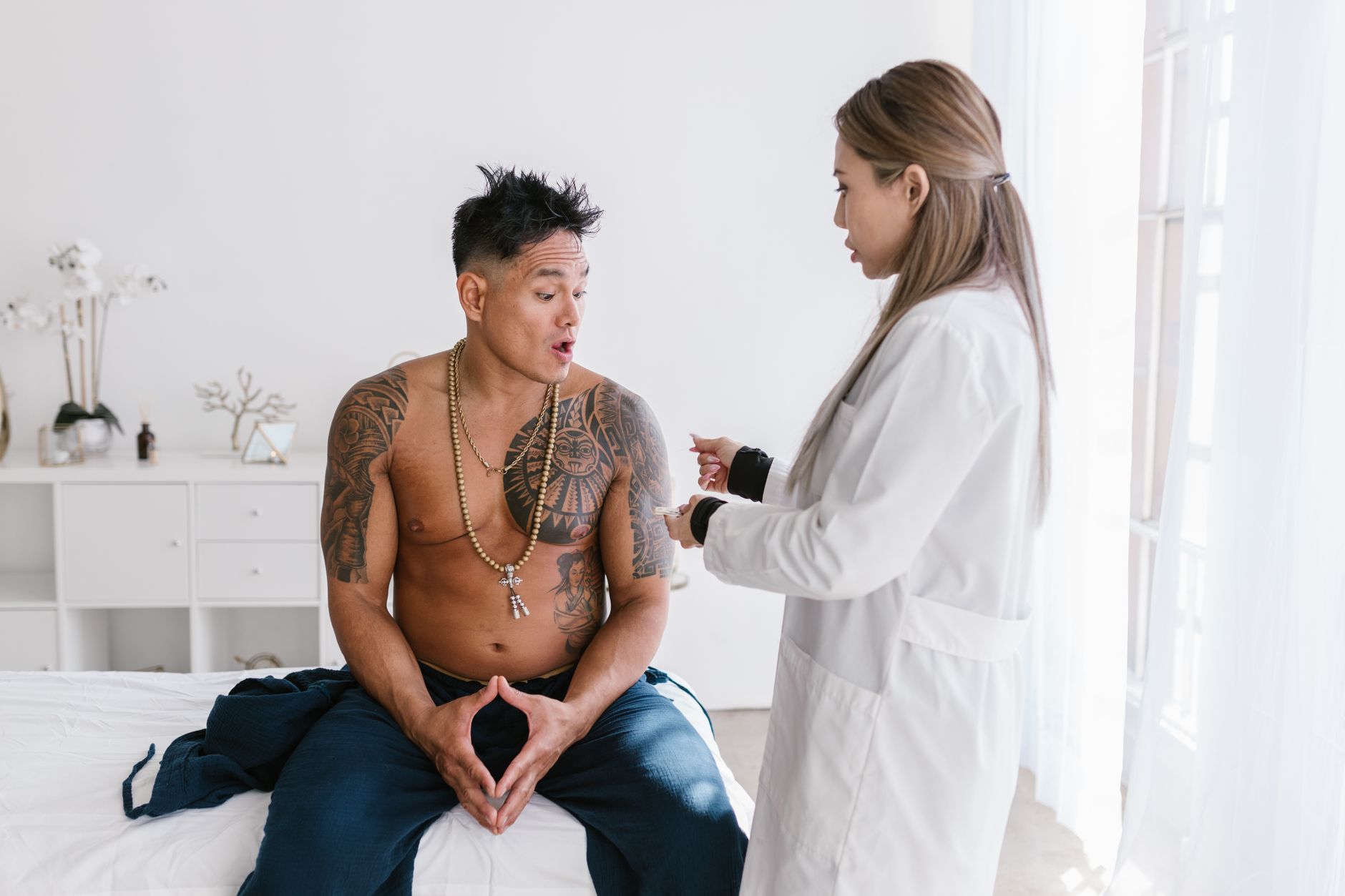 Female doctor talking to tattooed patient in modern clinic.